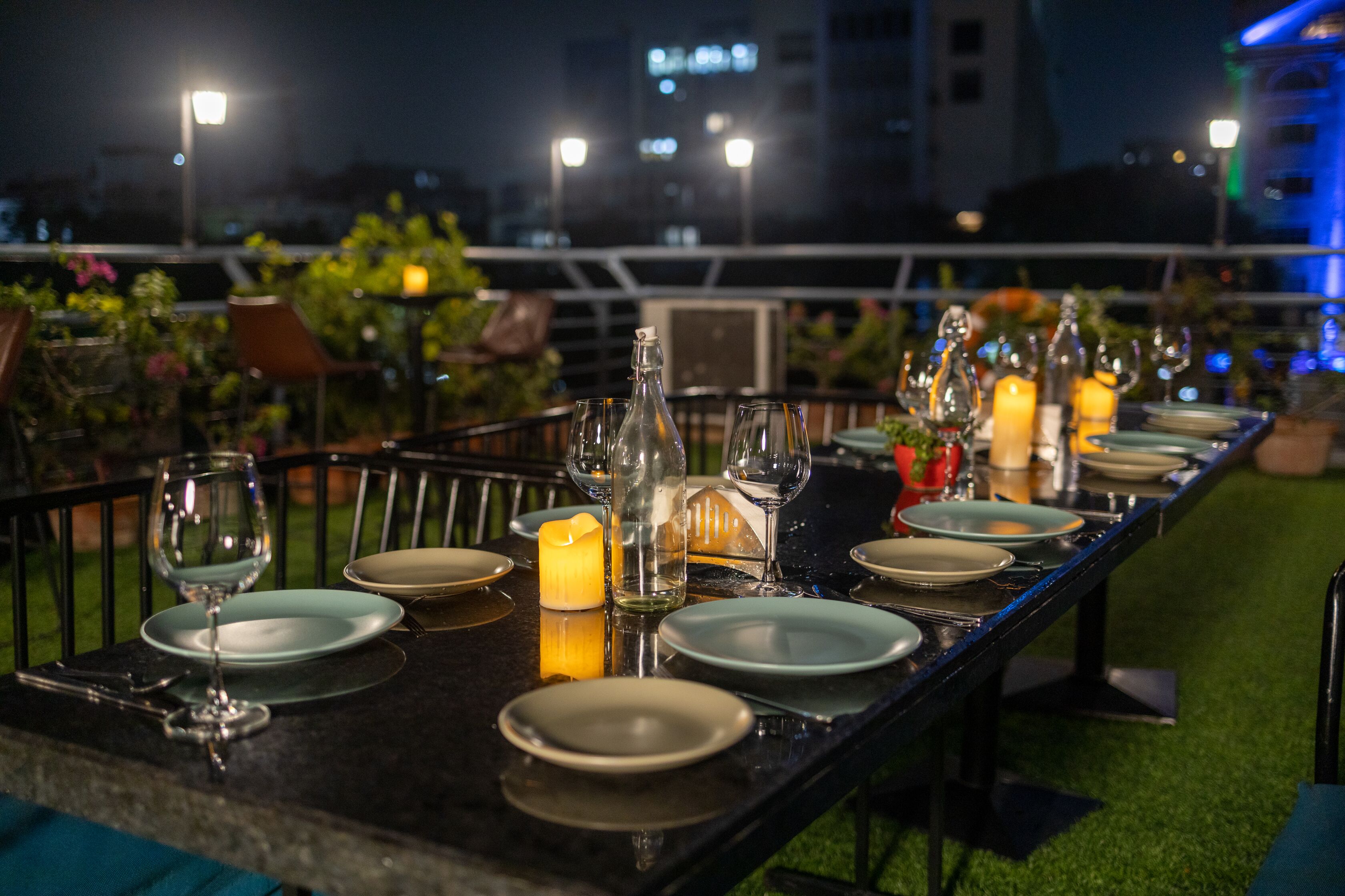 A long dining table set for a meal with candles, glasses, and plates.