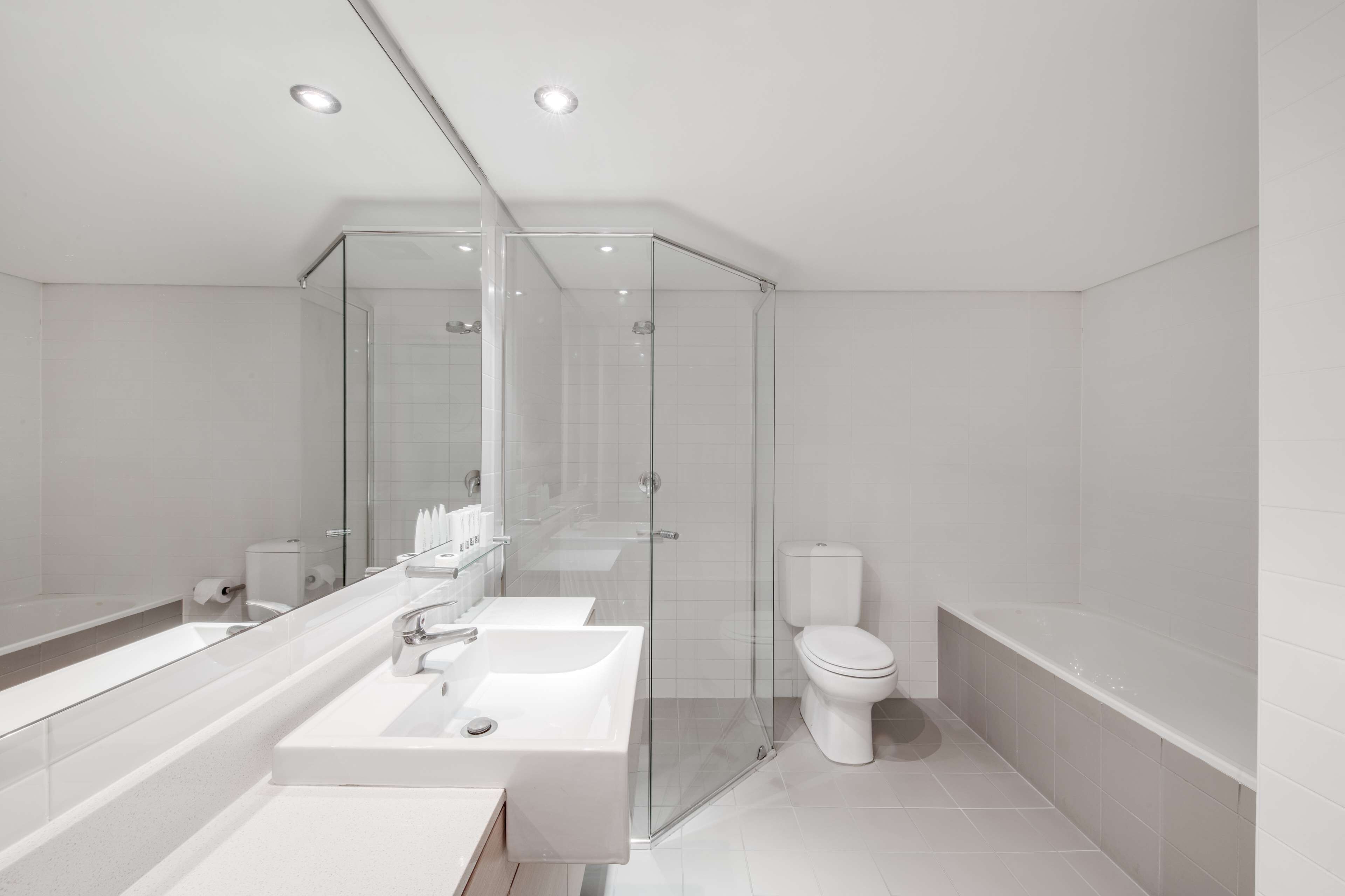 Ein modernes Badezimmer mit einer Glaskabine zur Dusche, einem großen Waschbecken und einer Toilette.