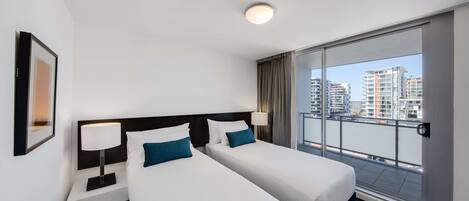 Habitación de hotel con dos camas, un ventanal grande y vistas a la ciudad, y una lámpara en el techo.