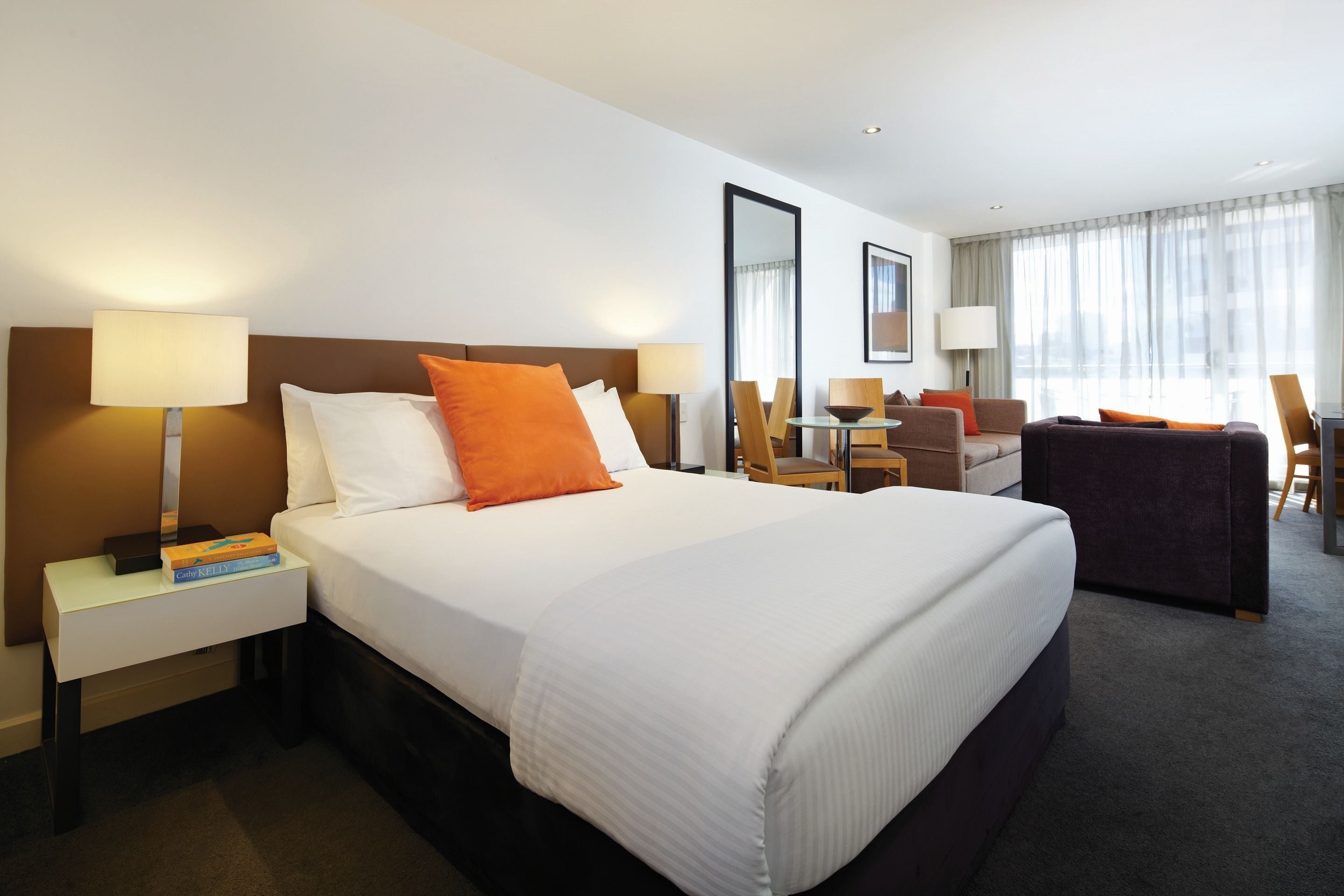 A hotel room with a large bed, two bedside tables, a desk, and a chair.