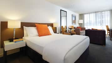 A hotel room with a large bed, two bedside tables, a desk, and a chair.