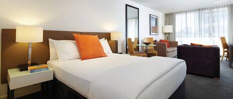 Een hotelkamer met een groot bed, twee nachtkastjes, een bureau en een stoel.