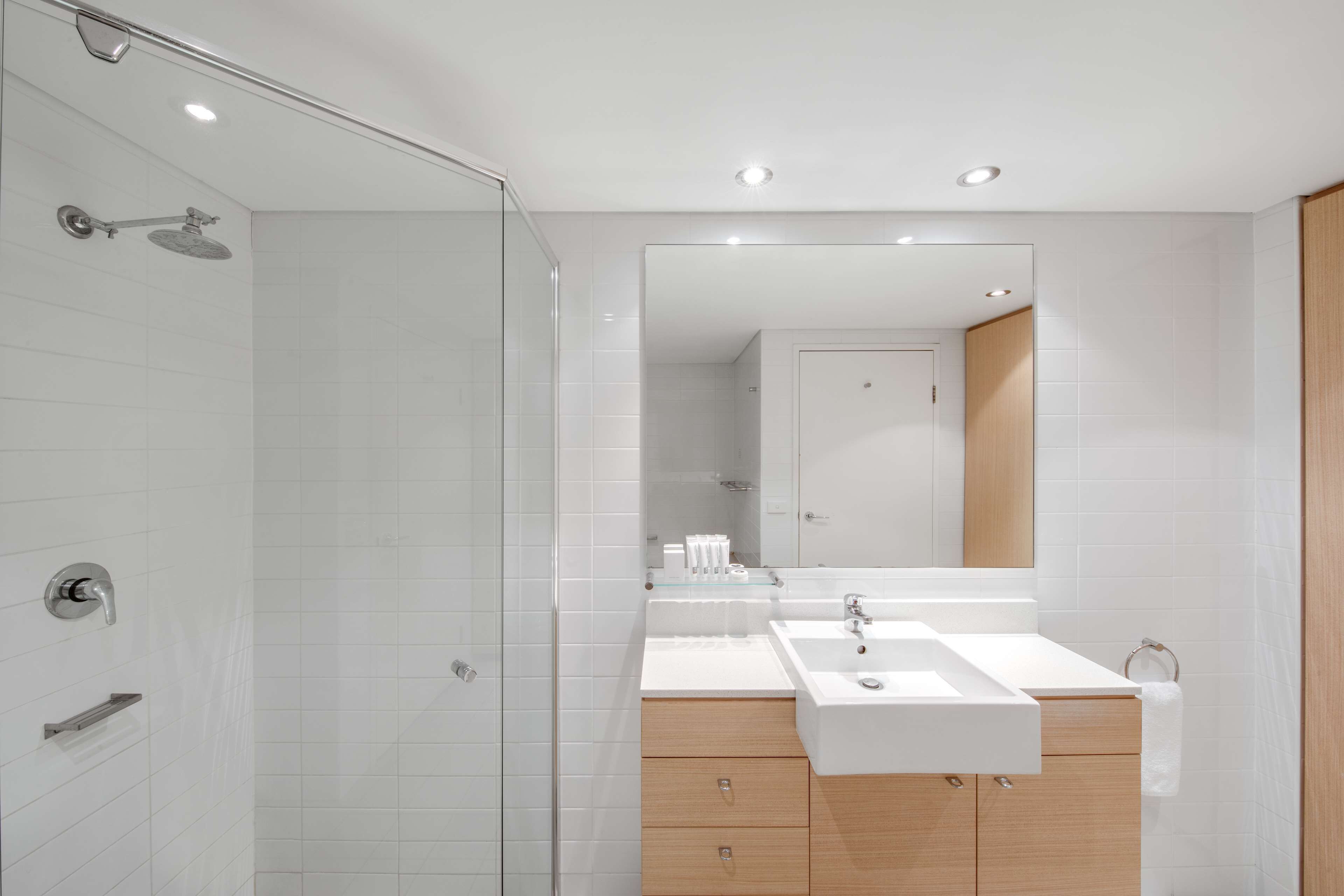 A modern bathroom with a glass shower enclosure, a double sink vanity, and a large mirror.