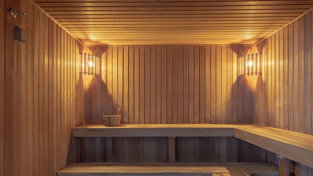 Puinen sauna, jossa on penkit ja seinään kiinnitetyt valaisimet.