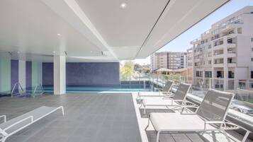 Una piscina al aire libre, sillones reclinables de piscina