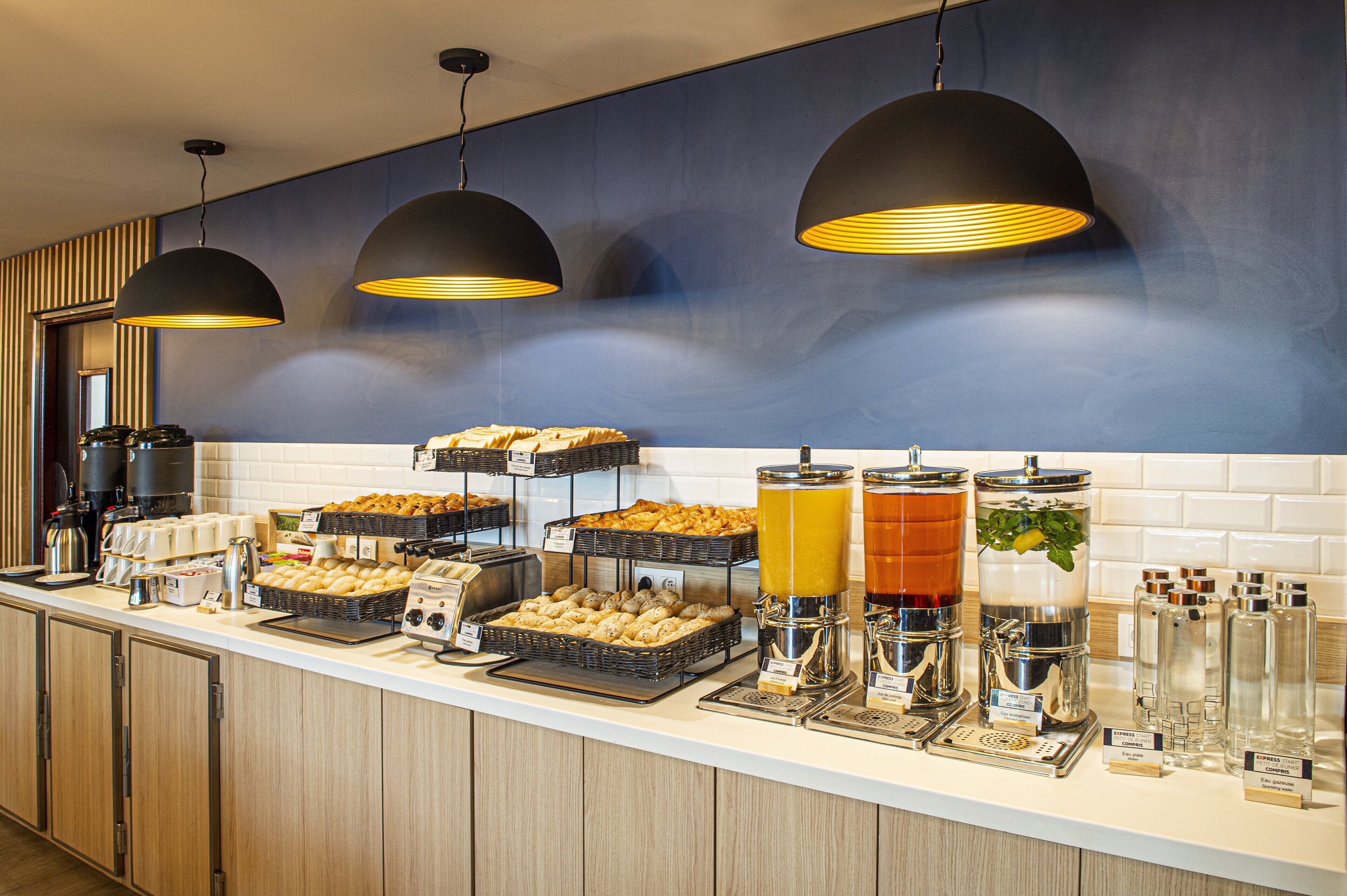 A breakfast buffet with various food items, coffee machines, and beverage dispensers.