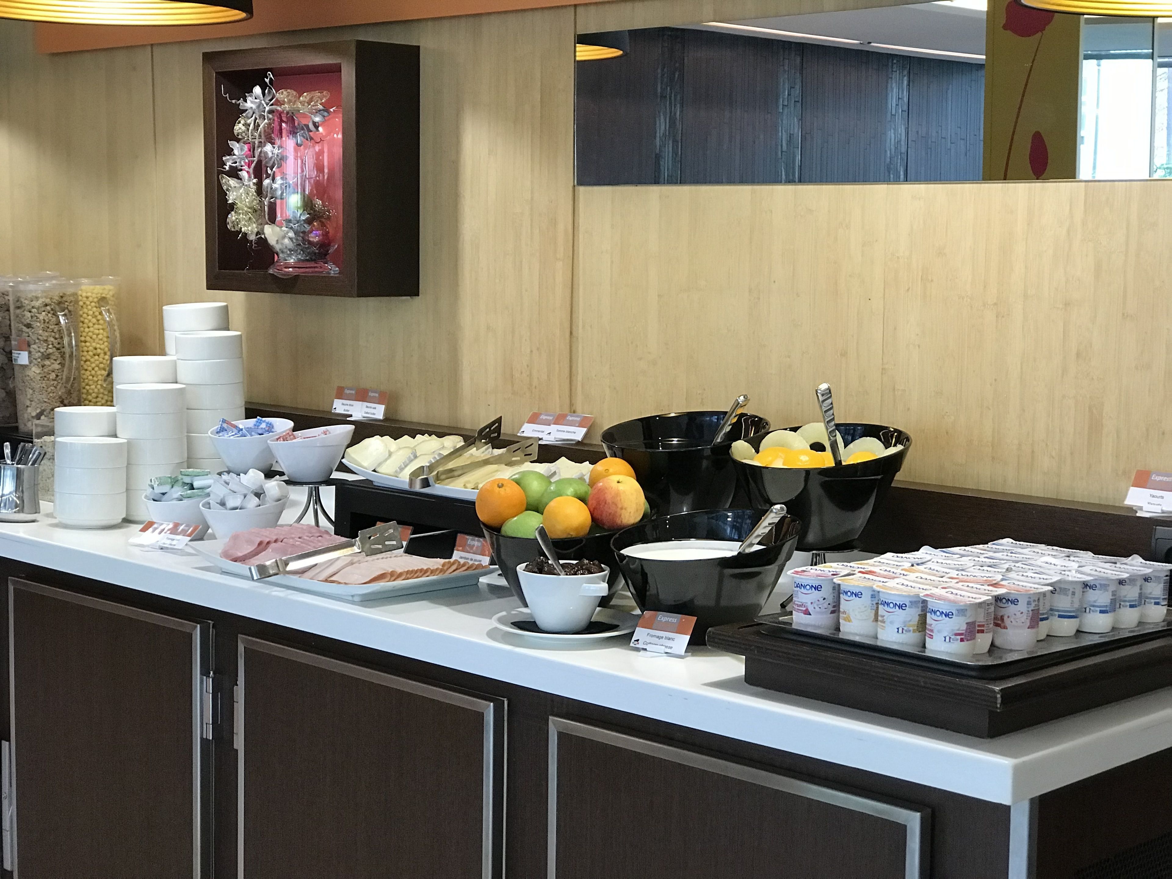 A buffet counter with various food items, including fruits, dairy products, and bread.