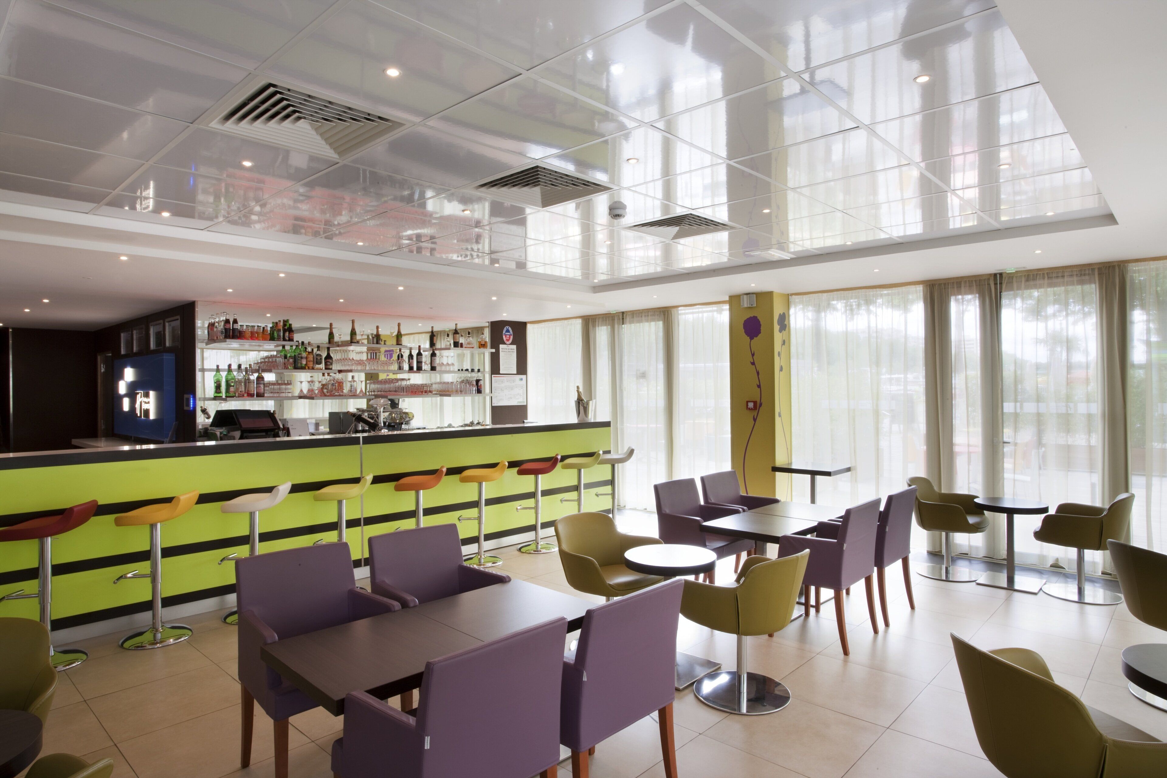 Un restaurante moderno con barra, techos altos y grandes ventanales.