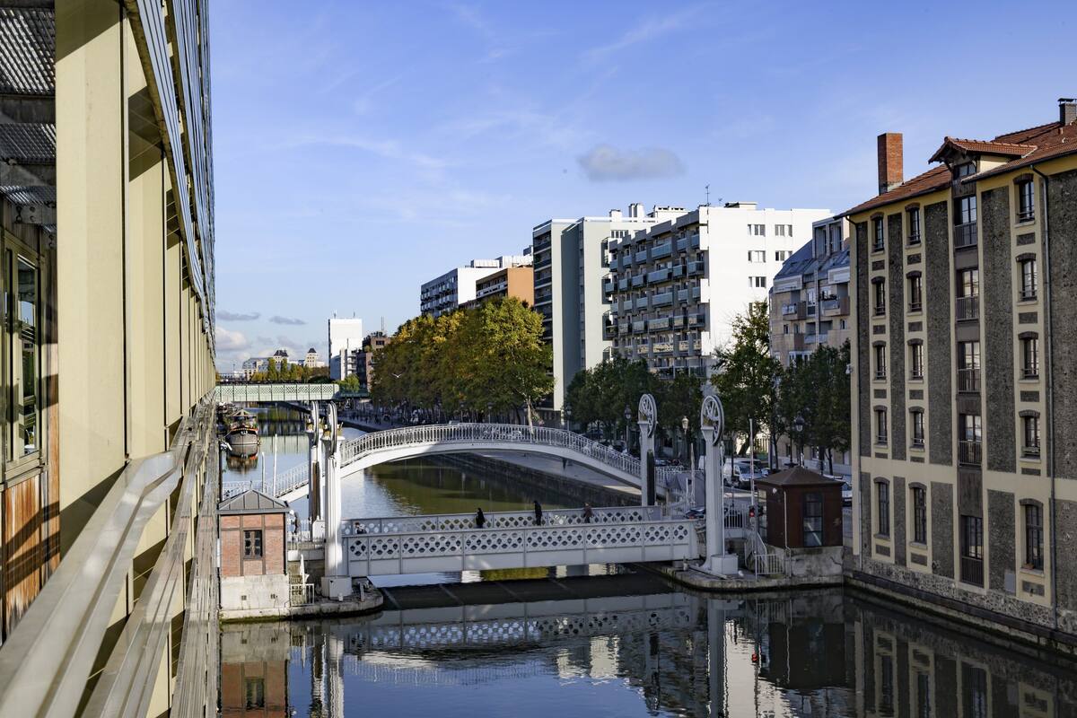 A canal with a white bridge, surrounded by buildings with balconies and a clear sky.