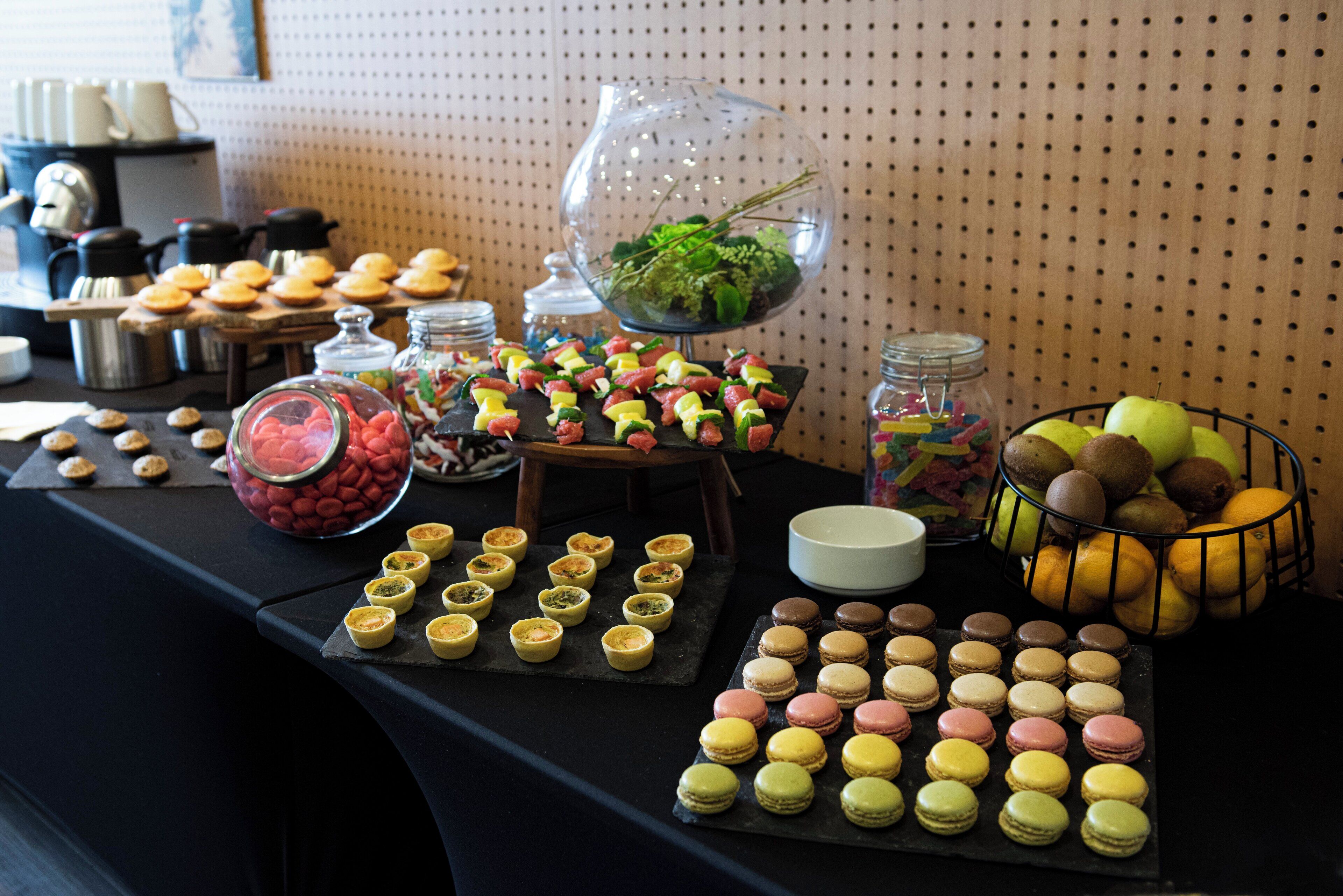 A buffet table with various food items including macarons, cookies, and fruits.