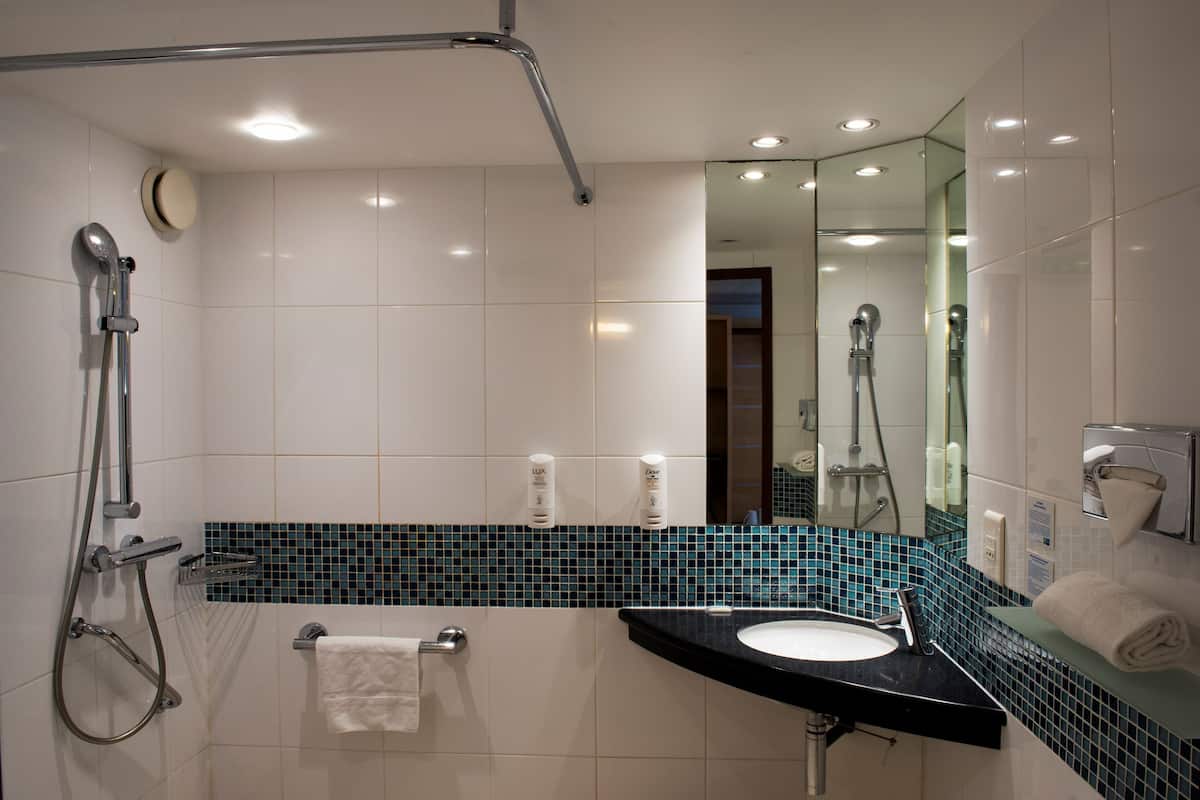 A modern bathroom with a shower, sink, and mirror.