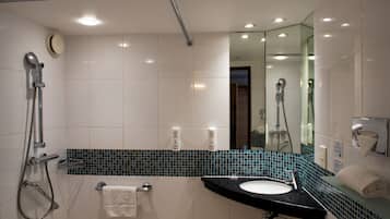 Een moderne badkamer met een douche, wastafel en spiegel.