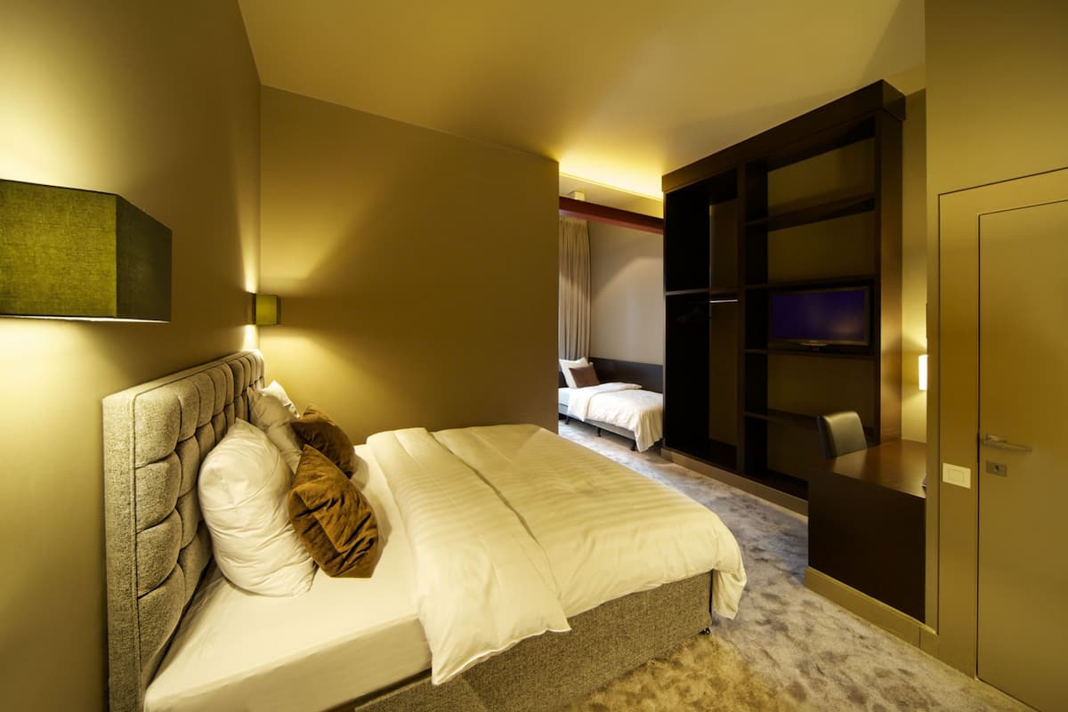 A hotel room with a large bed, a separate seating area, and a television.