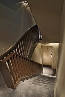 A modern staircase with a wooden handrail and carpeted steps leading to a door labeled "SAS 24".