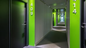 Un pasillo moderno con paredes verdes y números que se ñalan la ubicación de las habitaciones.