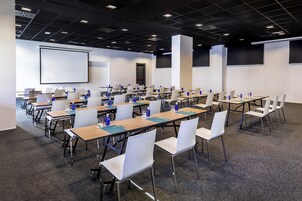 A conference room with multiple tables and chairs, equipped with laptops, water bottles, and glasses.