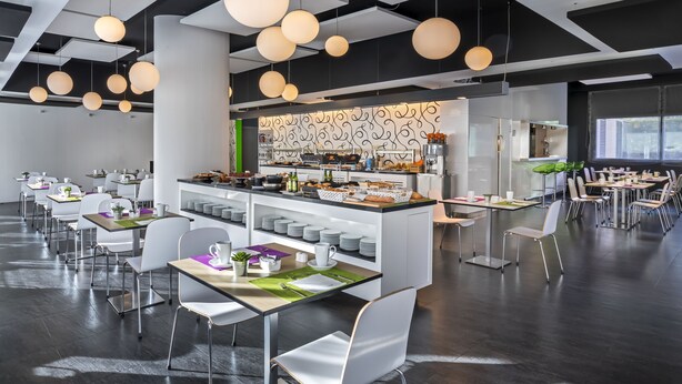 Un comedor moderno con lámparas colgantes redondas, sillas blancas y una estación de buffet central.