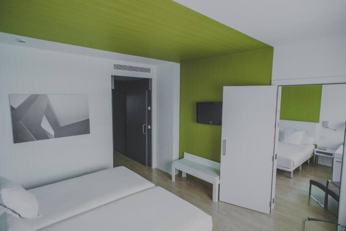 Een moderne hotelkamer met een bed, een bankje, een televisie en een kledingkast.