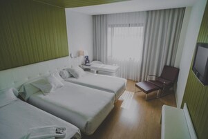 Habitación de hotel con dos camas, un escritorio, una silla y un televisor.