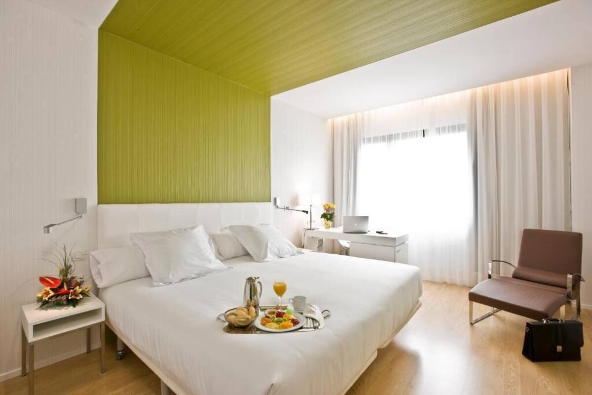 Een hotelkamer met een groot bed, een bureau, een stoel en een ontbijt karretje op het bed.