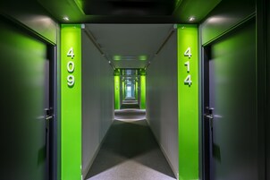 A hallway with green walls and numbers indicating room locations.