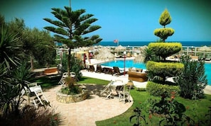 A pool area with lounge chairs and a view of the sea. - New Kydonia Suites & Studios (Chania)