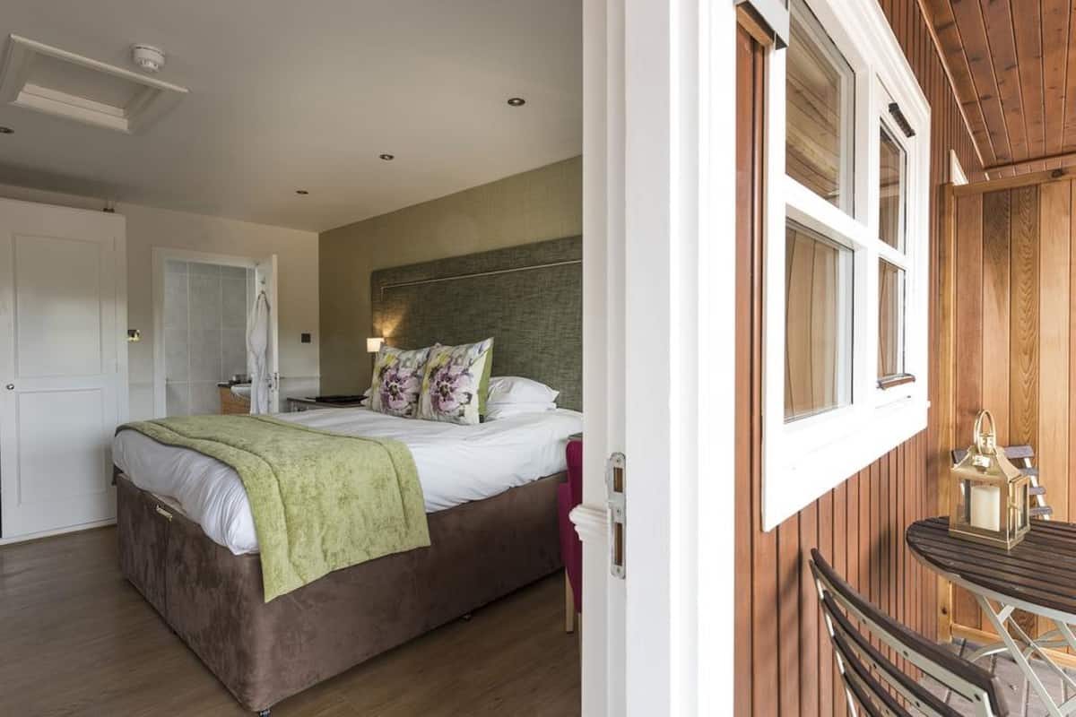 A bedroom with a bed, a bedside table, a lamp, and a window with wooden shutters.