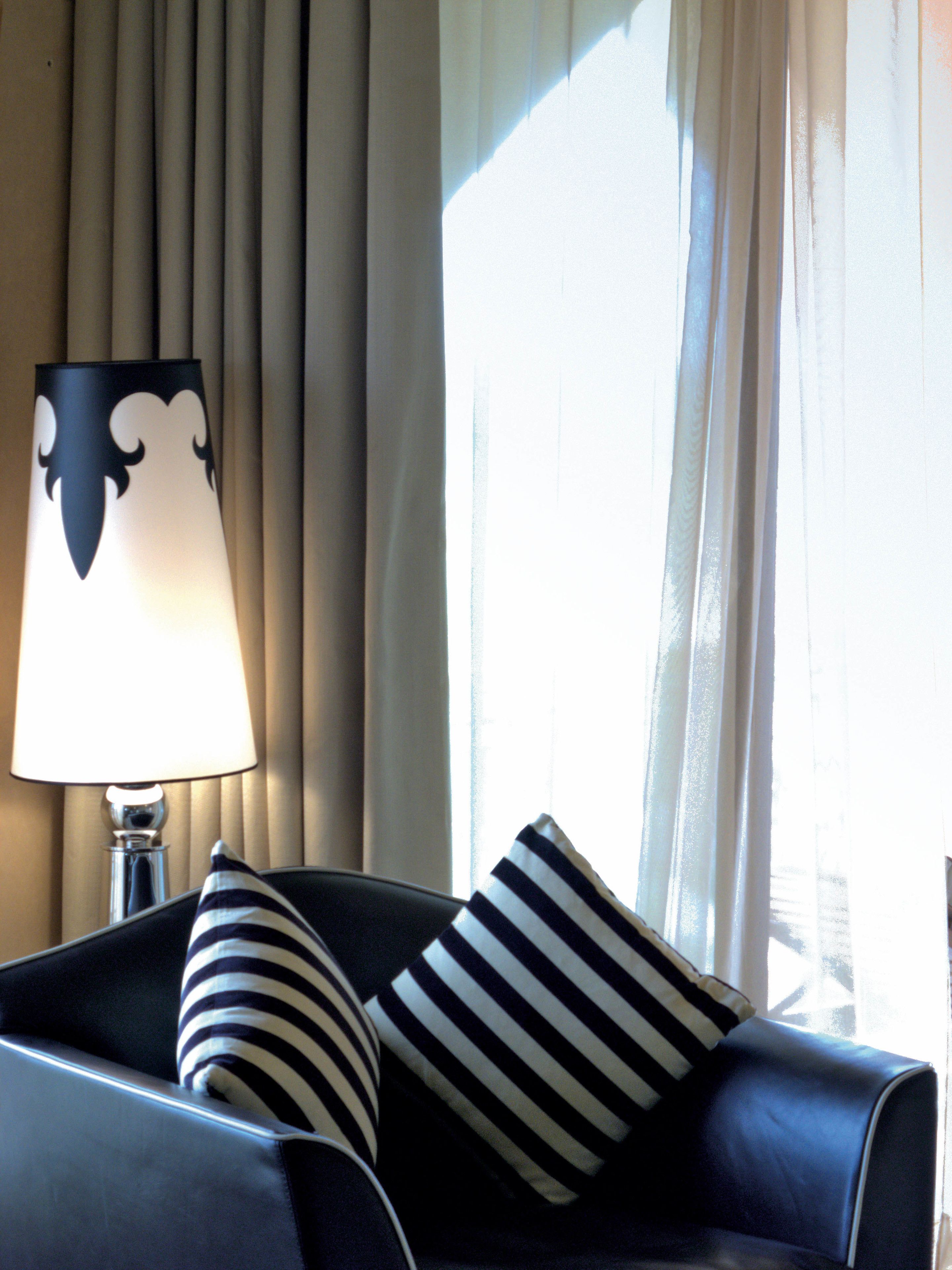 A room with a sofa, striped pillows, a lamp, and curtains.