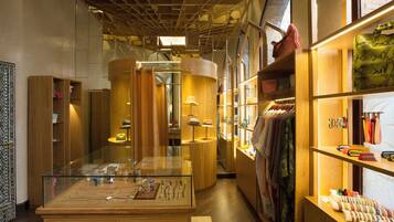 Interior de un hotel boutique con muebles de madera, una vitrina de cristal y percheros con ropa ordenada.