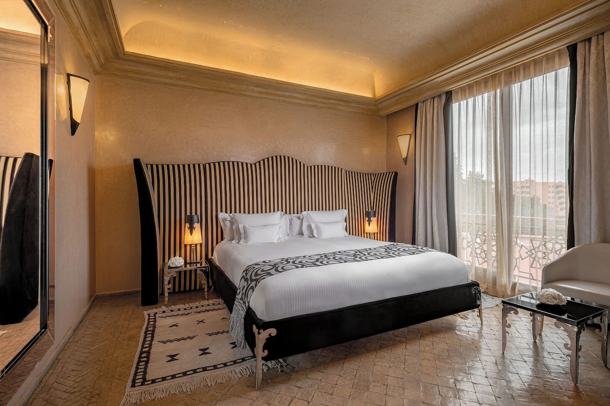 Una camera d'hotel con un letto grande, un'area salotto con un divano e un balcone con vista.