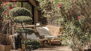 Pátio com área de estar, parede decorativa e diversas plantas.