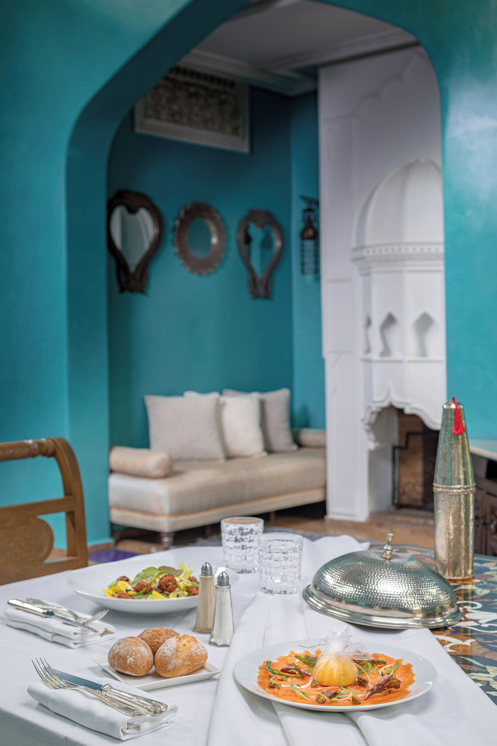 A dining table with plates of food, a salt and pepper set, and a glass of water.