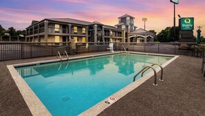 A hotel with a swimming pool, outdoor seating, and a view of the surrounding area. - Quality Inn White House (White House)