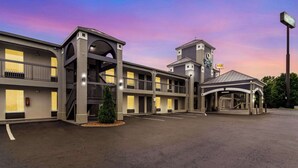 A multi-story hotel with a central atrium, outdoor seating area, and a parking lot. - Quality Inn White House (White House)