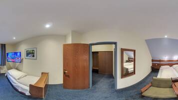 A hotel room with a bed, a desk, a chair, a TV, and a mirror.
