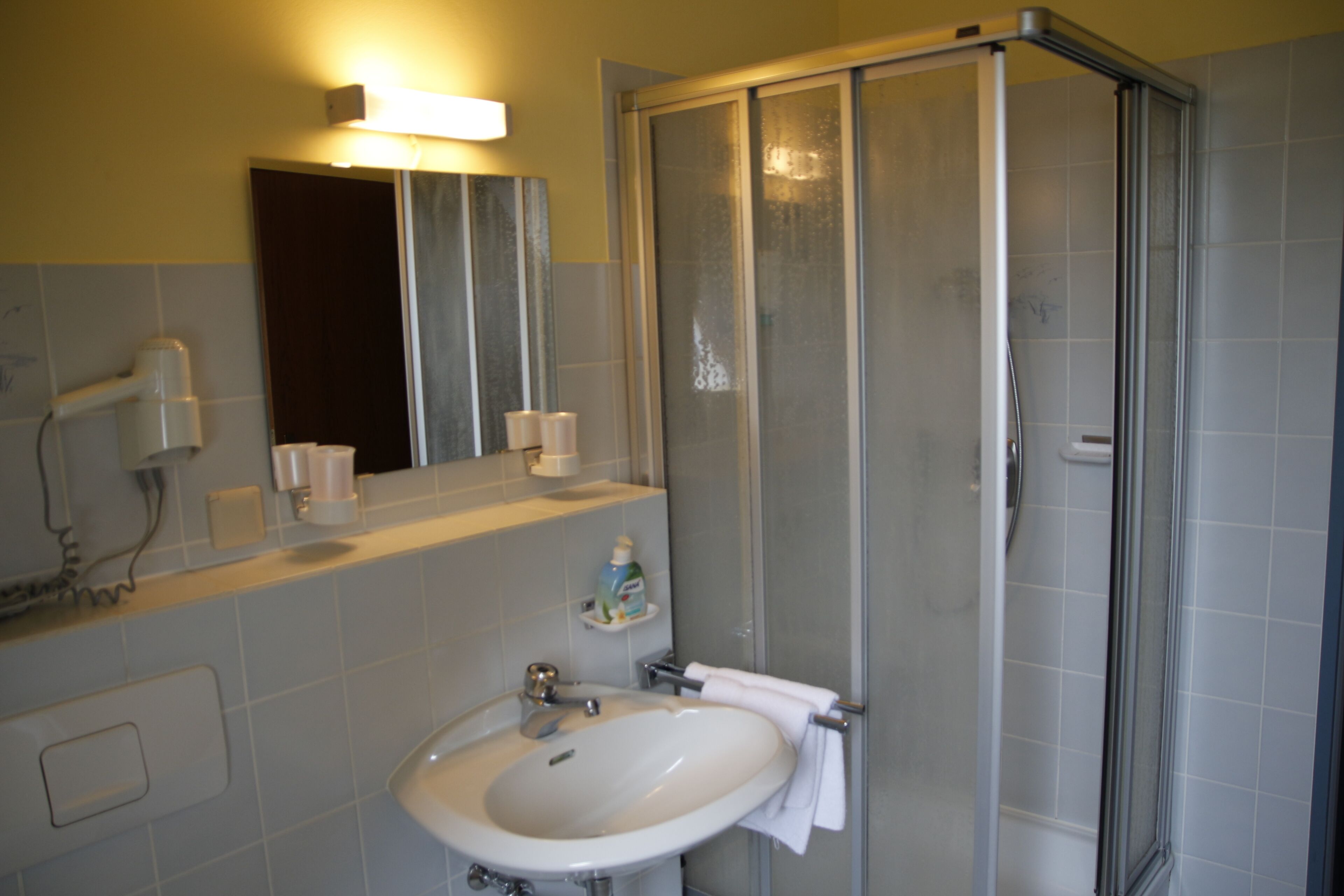 Een badkamer met een wastafel, spiegel en douchecabine.