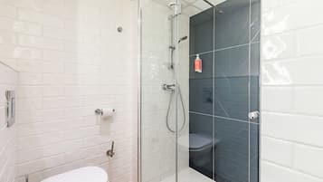 Een moderne badkamer met een douchecabine van glas, een wit toilet en een betegelde wand.