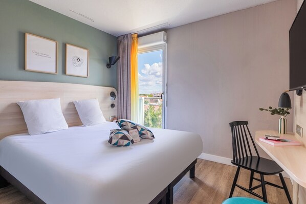 A hotel room with a bed, a desk, a chair, and a window with curtains. - Appart'City Confort Montpellier Gare Saint Roch (Montpellier)