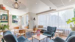 A modern lounge area with comfortable seating, a coffee table, and a floor lamp. - Appart'City Confort Montpellier Gare Saint Roch (Montpellier)