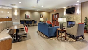 A hotel lobby with a seating area, a fireplace, and a television. - Comfort Suites Glendale - State Farm Stadium Area (Glendale)
