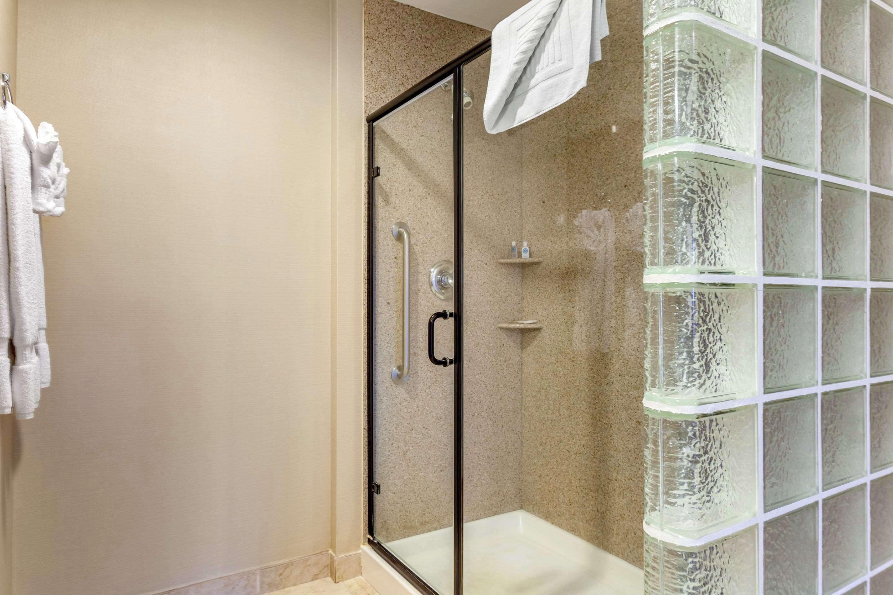 Een badkamer met een douchecabine van glas, een glazen douchemandje en een handdoekrek.