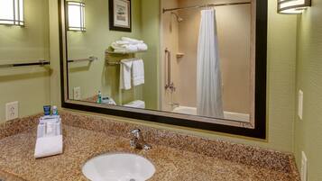 A bathroom with a granite countertop, a sink, a mirror, a towel rack, and a shower with a curtain.