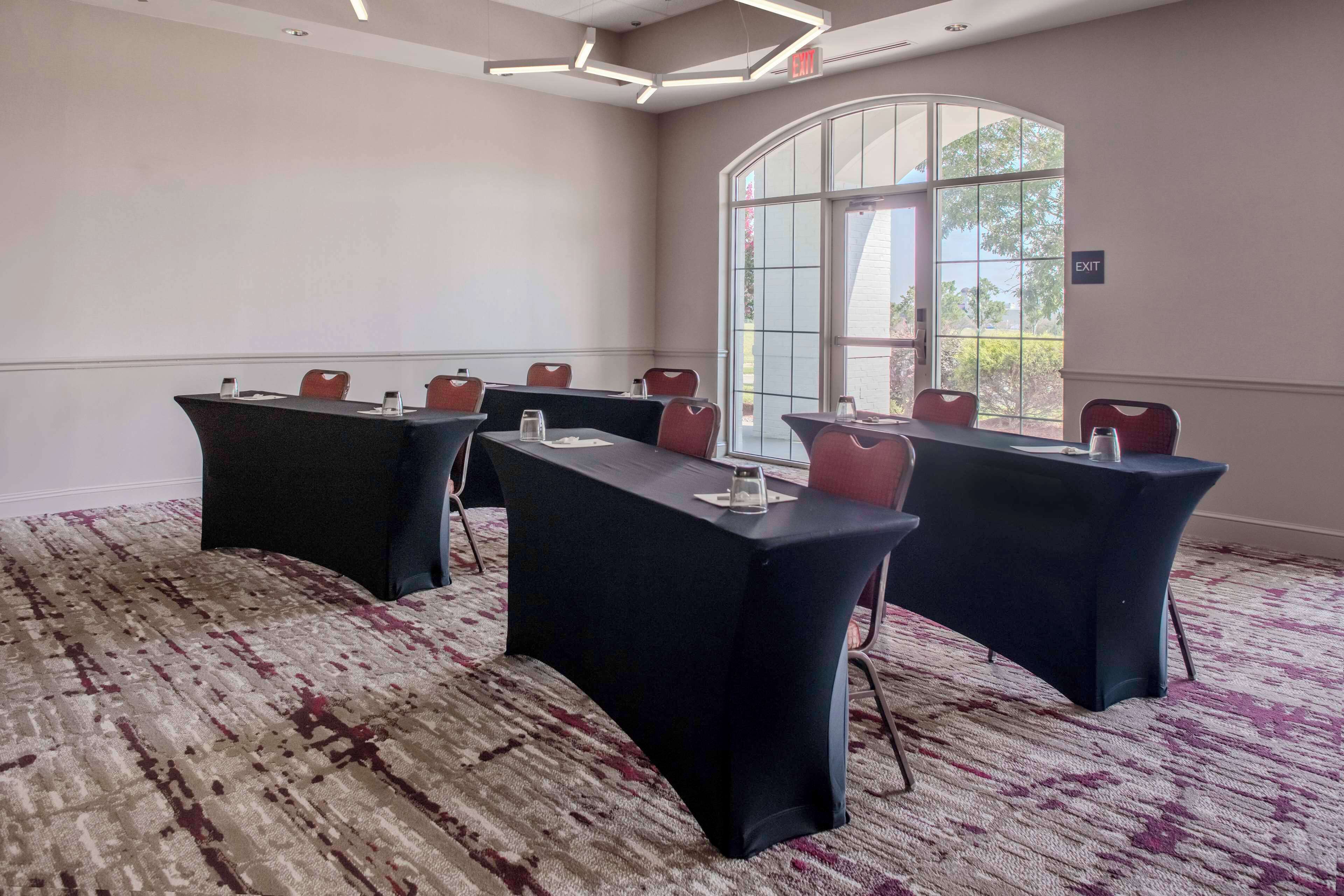 A conference room with a large table, multiple chairs, and a carpeted floor.