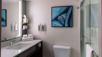 A modern bathroom with a large mirror, a sink, a toilet, and a glass shower enclosure.