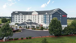 A large, multi-story Hilton Garden Inn with a central courtyard, a covered entrance, and a parking lot.