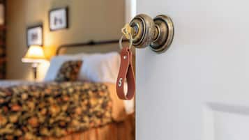 Eine Hotelzimmertür mit Schlüsselanhänger und ein Bett mit floralem Überwurf.