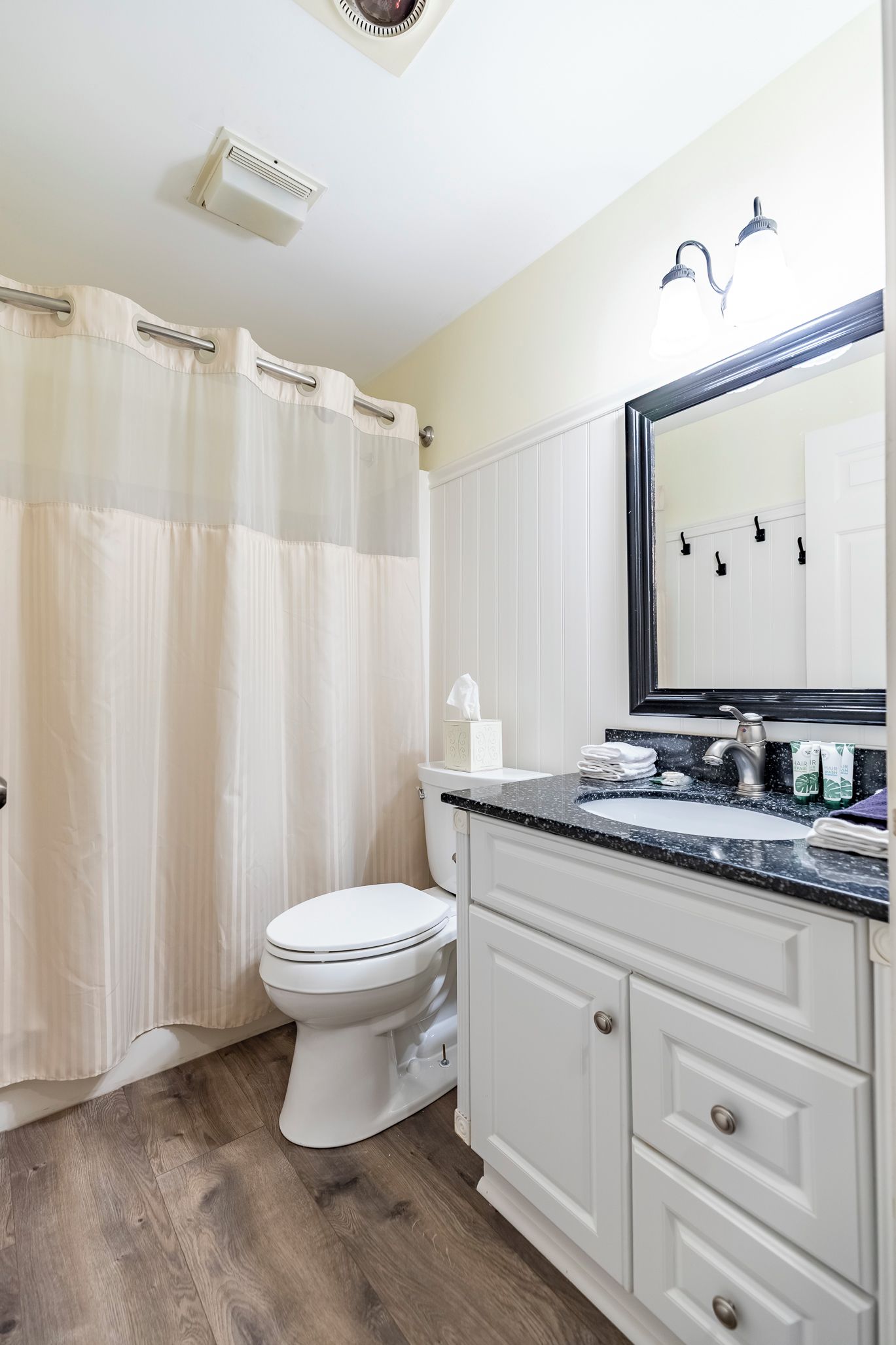 Un baño con inodoro, lavamanos con espejo y cortina de ducha.