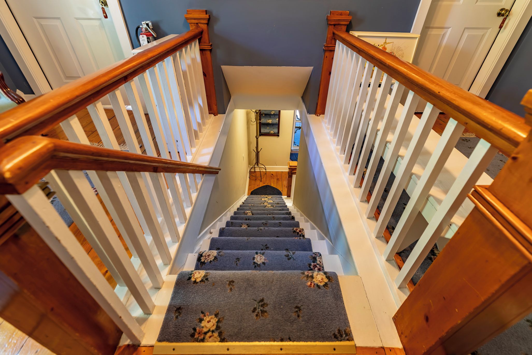 A wooden staircase with white railings leading to a landing.