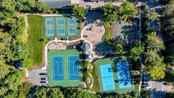 Ovenfra ses et boligområde med flere tennisbaner, parkeringsplads og grøn bevoksning omkring.
