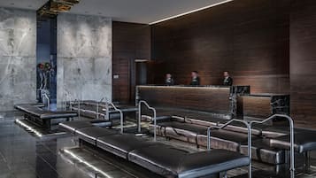 A modern lobby with a reception desk, leather seating, and a marble wall.